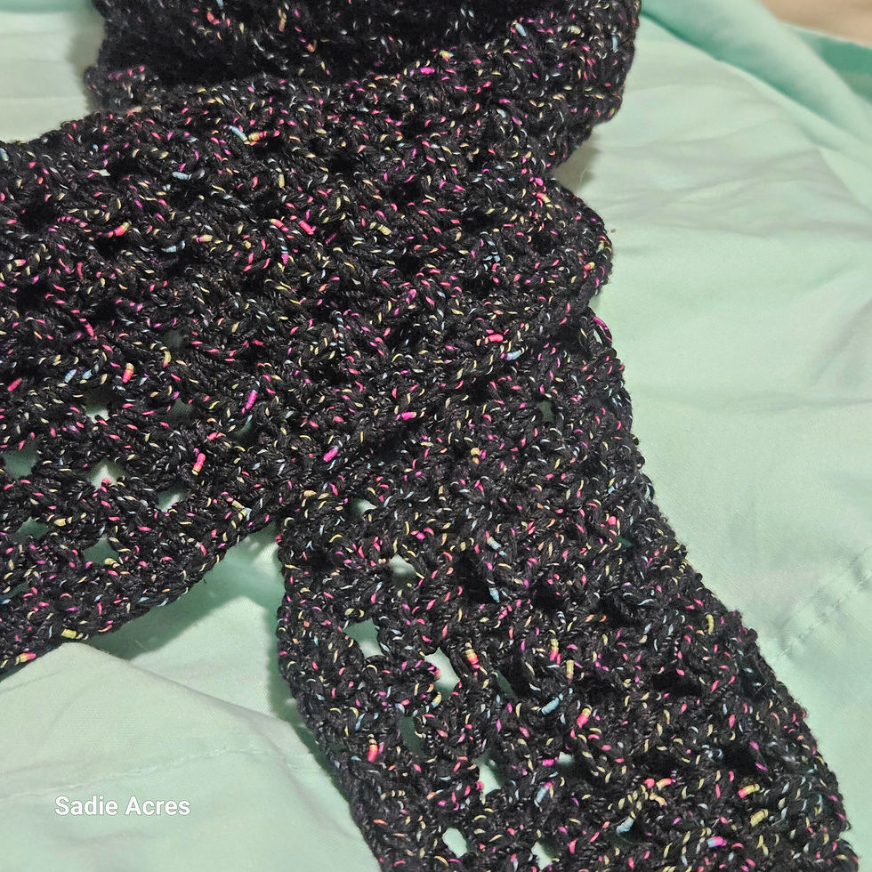 Thumbnail: Dark speckled crocheted scarf on blue fabric