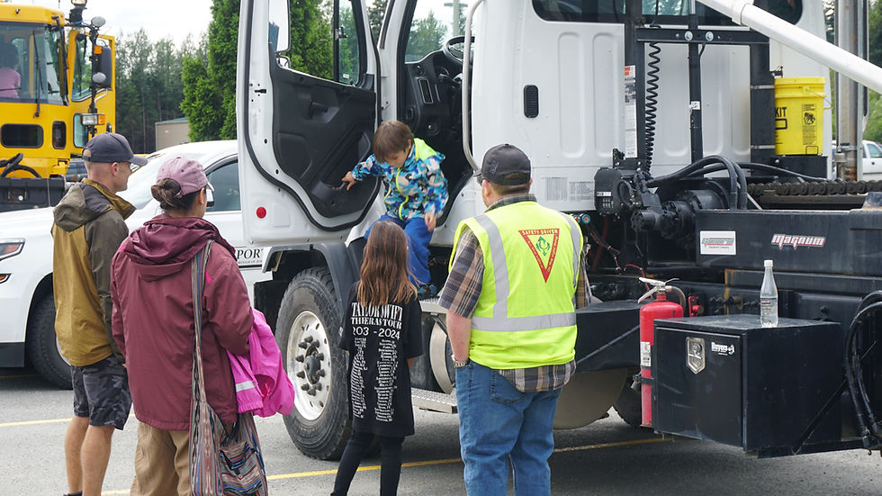 A child climbs out of the cab of an Alaska Waste truck at Trucks N' Stuff at Dimond Park on Saturday, July 12, 2025. (Ellie Ruel / Juneau Independent)