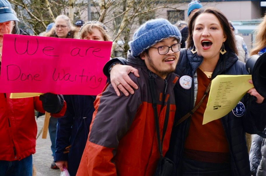 Fu Bao Hartle, left, participates in the Key Campaign in front of the Alaska State Capitol on March 18, 2026, with Nikki Bass, a member of the Key Coalition of Alaska who nominated Hartle for an Advocate of the Year award he is receiving from Southeast Alaska Independent Living on Saturday. (Photo by Clare Pavia)