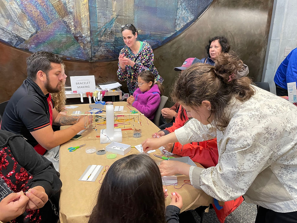 Ellen Carrlee (back), conservator of the Alaska State Libraries, Archives and Museums, guides participants creating bracelets on fish line using colorful glass beads, porcupine quills, salmon bones and naturally dyed wool during a Family Fun Fair on Friday, July 11, 2025. (Laurie Craig / Juneau Independent)