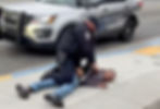 A Juneau Police Department officer restrains a man who was injured while being arrested near the Douglas Public Library on Thursday, July 31, 2025. (Screenshot from video by Ibn Bailey)