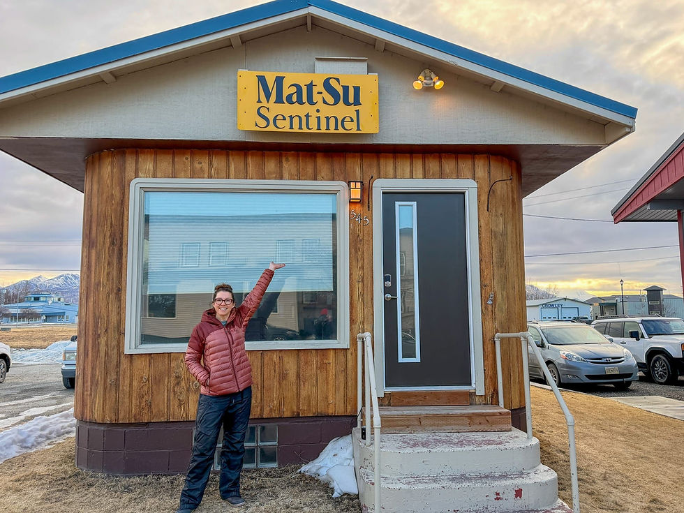 Mat-Su Sentinel founder Amy Bushatz shows the Sentinel's new Mountain Top Metal Co.-crafted sign and Palmer-based headquarters on April 6, 2026. (Mat-Su Sentinel photo)