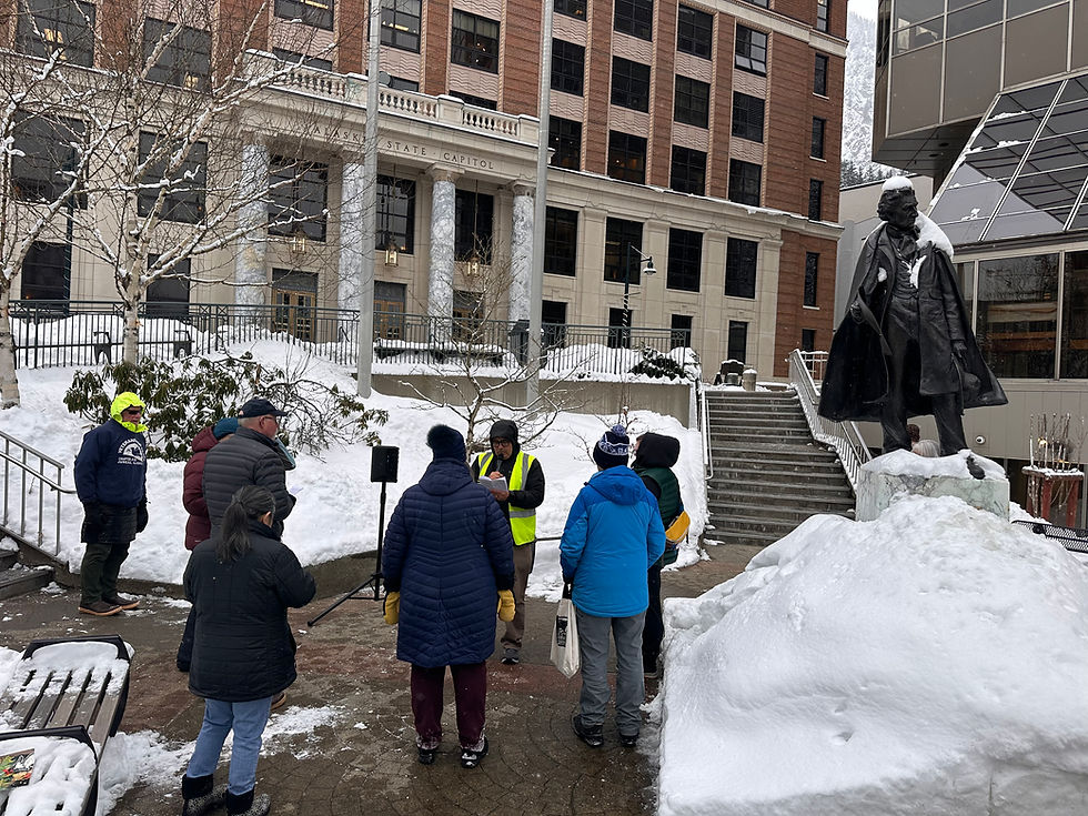 People critical of actions and votes by U.S. Rep. Nick Begich III, R-Alaska, read the U.S. Constitution aloud outside Dimond Courthouse on Tuesday, March 10, 2026, before his speech to the Alaska Legislature at the state Capitol. (Mark Sabbatini / Juneau Independent)