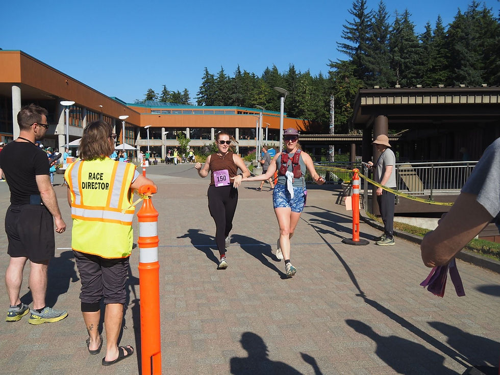 Jo Thompson and Sierra Kryzer hold hands to cross the finish line at the Beat the Odds 5K run at the University of Alaska Southeast campus on Saturday, Aug. 15, 2026.  “I think we all have family and friends who had cancer and needed support, but we might too at some point,” Kryzer said. (Natalie Buttner / Juneau Independent)