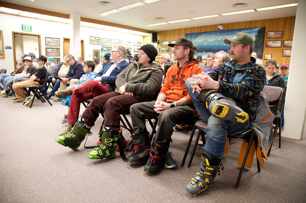 Audience members wear ski boots and other gear to show their support for continued funding of Eaglecrest Ski Area during a Juneau Assembly Finance Committee meeting on Wednesday, May 13, 2026. (Mark Sabbatini / Juneau Independent)