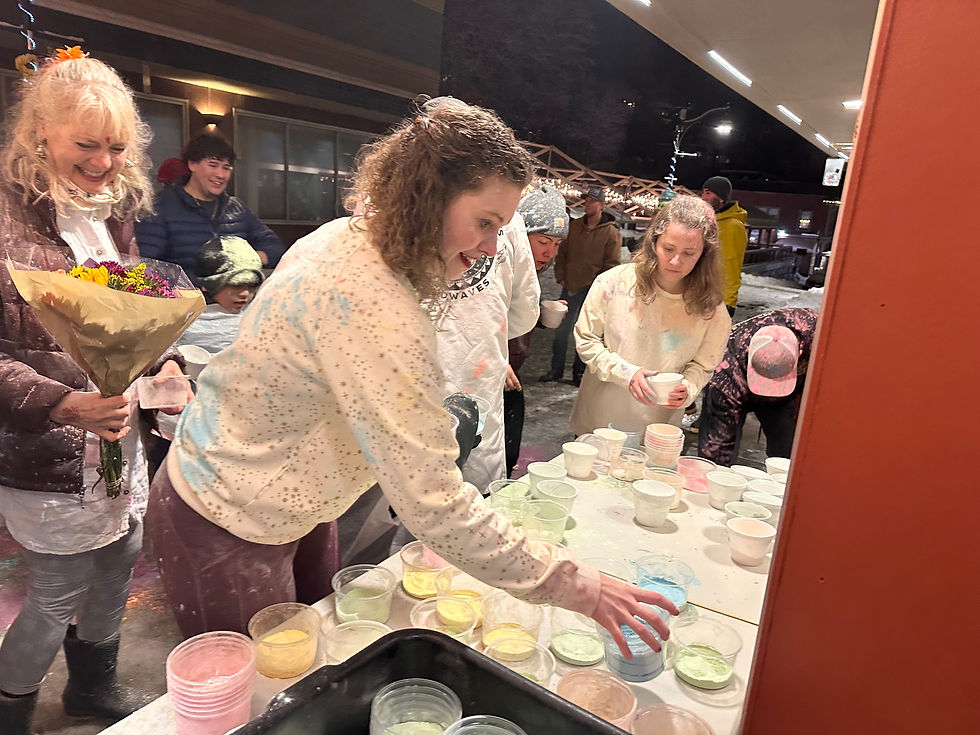 People grab cups of colorful powder from tables outside Spice Juneau Indian Cuisine during a Holi festival on Monday, March 23, 2026. (Mark Sabbatini / Juneau Independent)