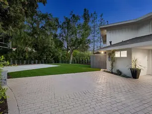 front yard curb appeal with pavers highlighting a light-colored driveway and landscaped lawn.