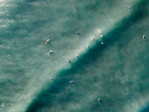 An aerial view of surfers gathering around a wave