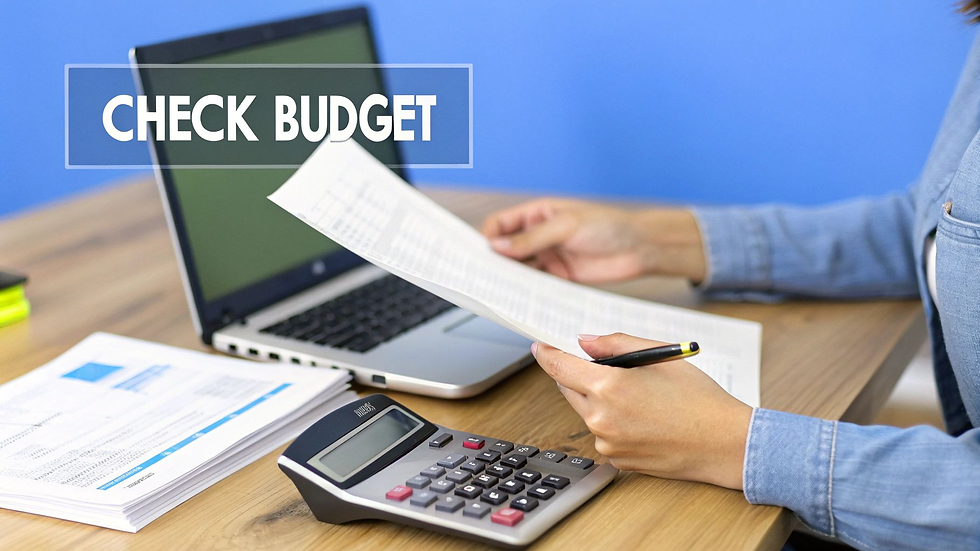 A woman holding a white piece of paper with a black pen in her left hand, resting her arms on a wood table with a laptop and calculator and words on the image that says Check Budget.