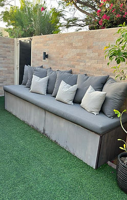  A cozy backyard scene featuring a bench adorned with pillows and a vibrant plant nearby, inviting relaxation and comfort.