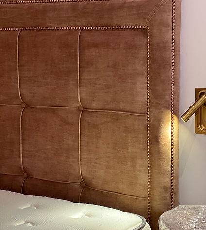 A cozy bed with a stylish headboard and a bedside lamp, creating a comfortable and inviting atmosphere.