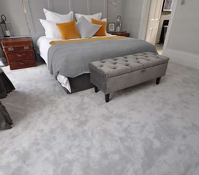 A spacious bedroom featuring a large bed adorned with a stylish grey and yellow bedspread, creating a cozy atmosphere