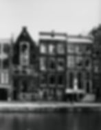 Historic canal houses in black and white, with large windows and intricate brickwork. The building is Anne Frank's father, Otto Frank's workplace, Opekta.