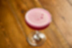 A refreshing pink drink on a wooden table, perfect for enjoying with Crust Bros Pizza London.