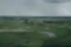 Aerial view of the Okavango Delta in Botswana during December, with seasonal floodplains, water channels, storm clouds and a helicopter in the distance.