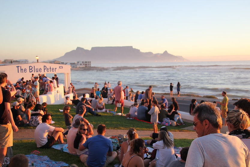 People sitting on the grass and enjoying the view at sunset at Blue Peter.