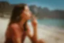 Woman smoking cannabis on Camps Bay beach with the Twelve Apostles mountains in the background.