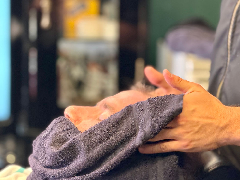 Barber pressing a hot towel over a client's face before a straight razor shave at Barbery Coast