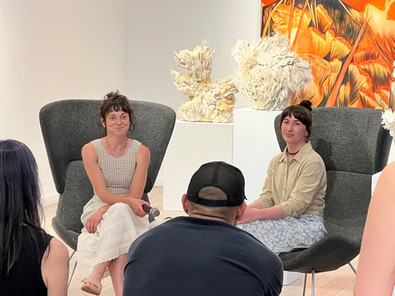 Artists Molly Altman and Sabrina Piersol participate in a public discussion during the Floral Panic exhibition at Art Base in Basalt, Colorado, surrounded by vibrant floral-inspired artwork and sculptural pieces.