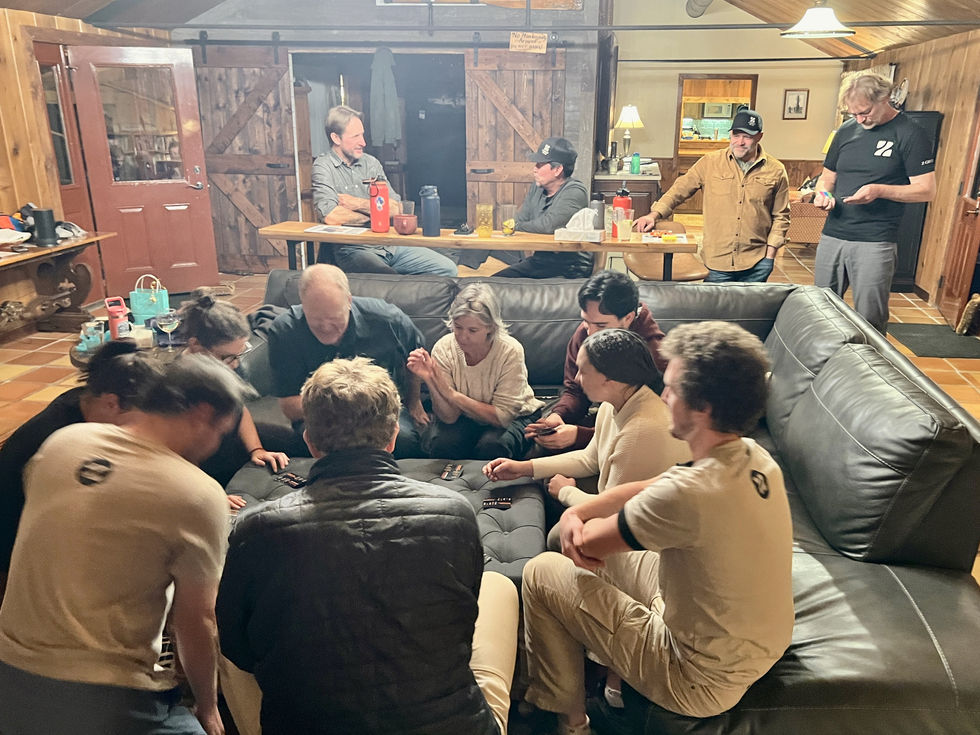 Z Group team members gathered around a cozy living room during their Moab retreat, focused on a group card game. The setting features rustic interiors and relaxed camaraderie, capturing a moment of connection and creativity outside the office.