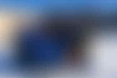 Group portrait of the Aspen Snowmass team and project collaborators in front of the Elk Camp lift shack, designed by Z Group. Smiling and dressed in ski gear, the team stands under bright winter sunlight, celebrating the project’s completion against the sleek, modern lift structure.