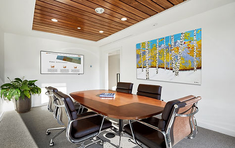 Contemporary home nestled at the base of Shadow Mountain in Aspen, Colorado, illuminated against the twilight sky with its modern glass façade and terraced landscape design.