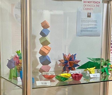 Photo of a display cabinet, full of origami.