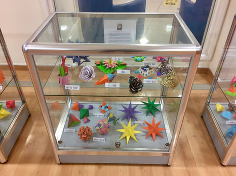 Photo of a display cabinet, full of origami.