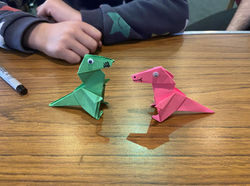 A photo showing a green T-Rex facing off against a red T-Rex. My money is on Red.