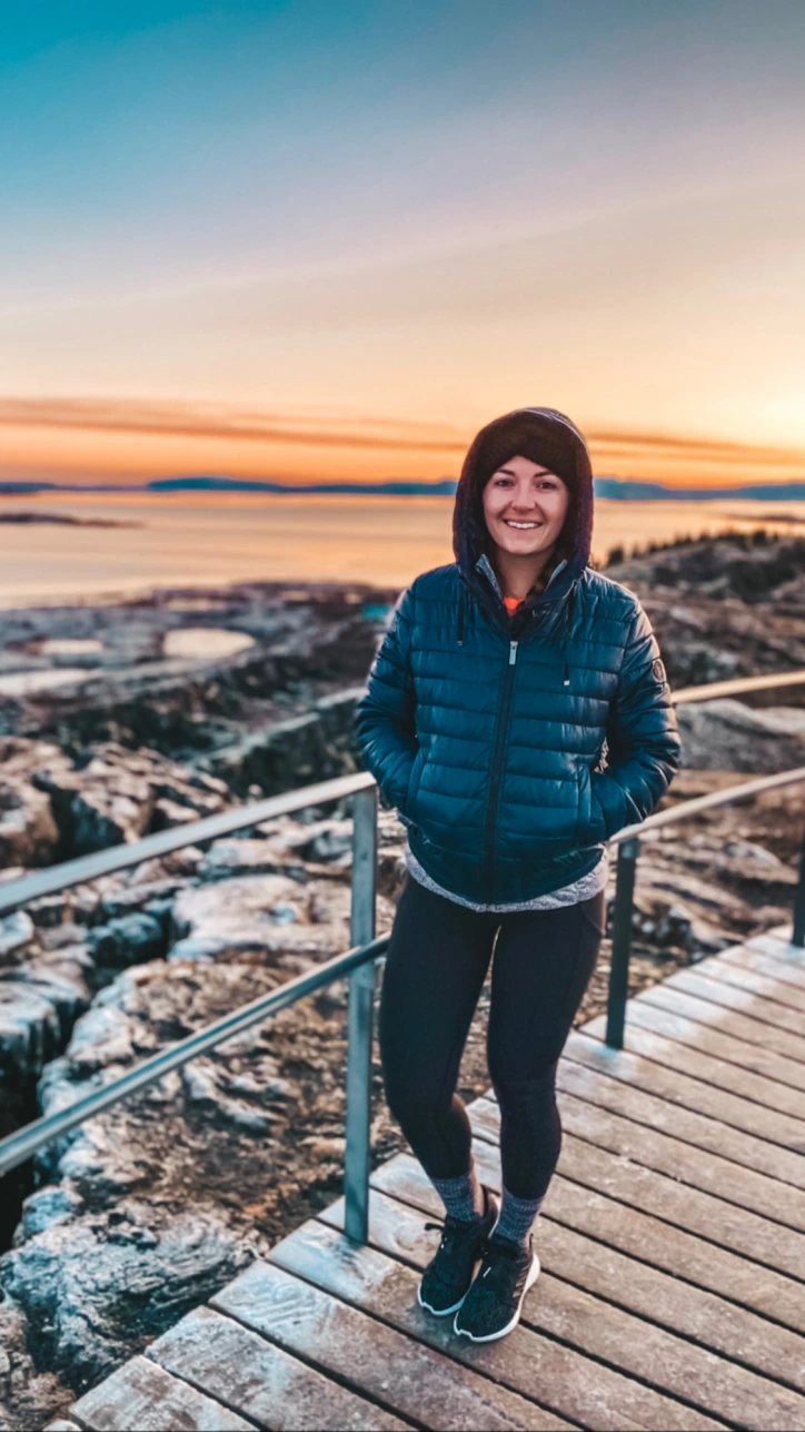 Girl in winter clothes posing in front of a sunset