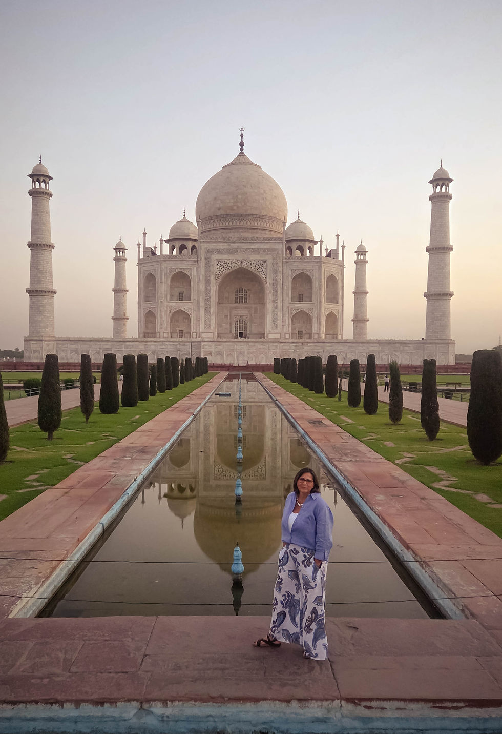 Britta stands at the Taj Mahal's reflecting pool in the first quiet light of morning, the marble dome rising behind her exactly as every traveler hopes it will. Photo by Leigh Sassone