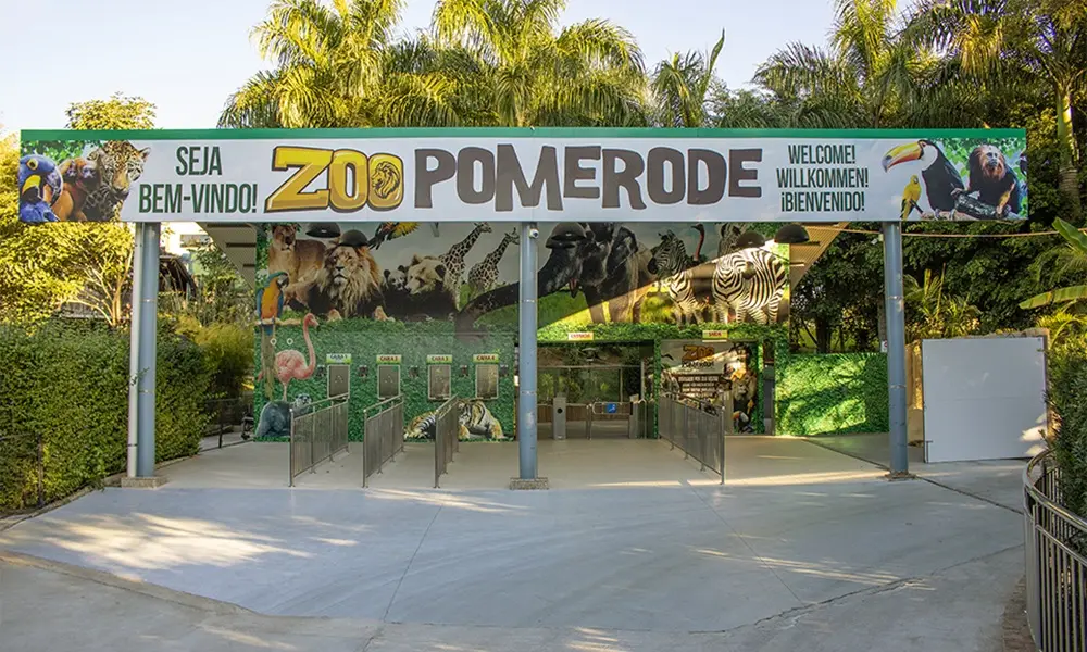 Fachada do Zoológico de Pomerode com letreiro, jardins bem cuidados e visitantes na entrada; atração turística familiar em Santa Catarina.