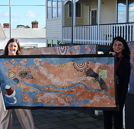 2 women holding aboriginal artwork