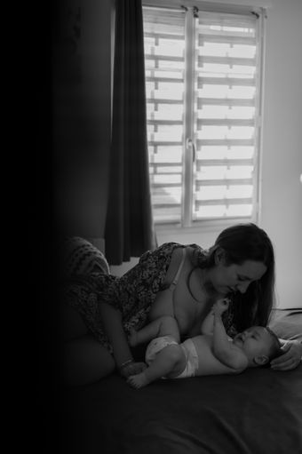Photo noir et blanc de maman et son bébé sur le lit Séance photo maman et bébé à domicile Yvelines 78