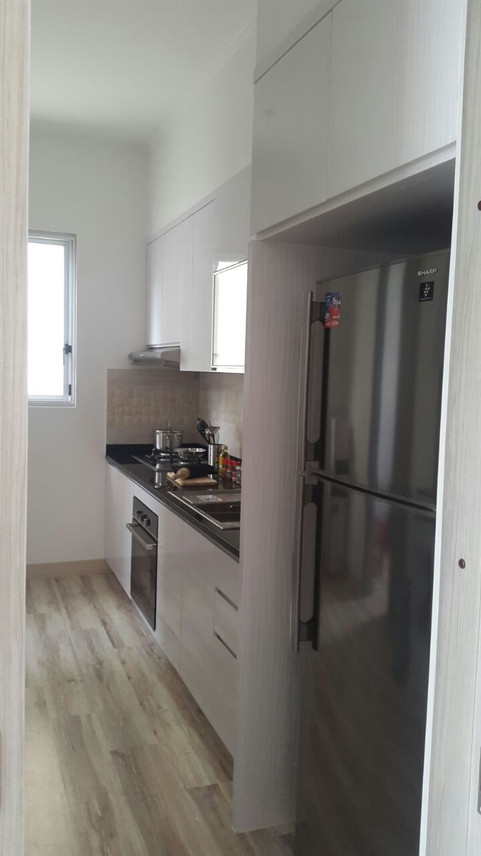 kitchen of a residential home in jakarta. complete with the refrigerator and wood motif floor.