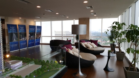 Marketing gallery seats facing windows with lamp, sofa, miniature of building.