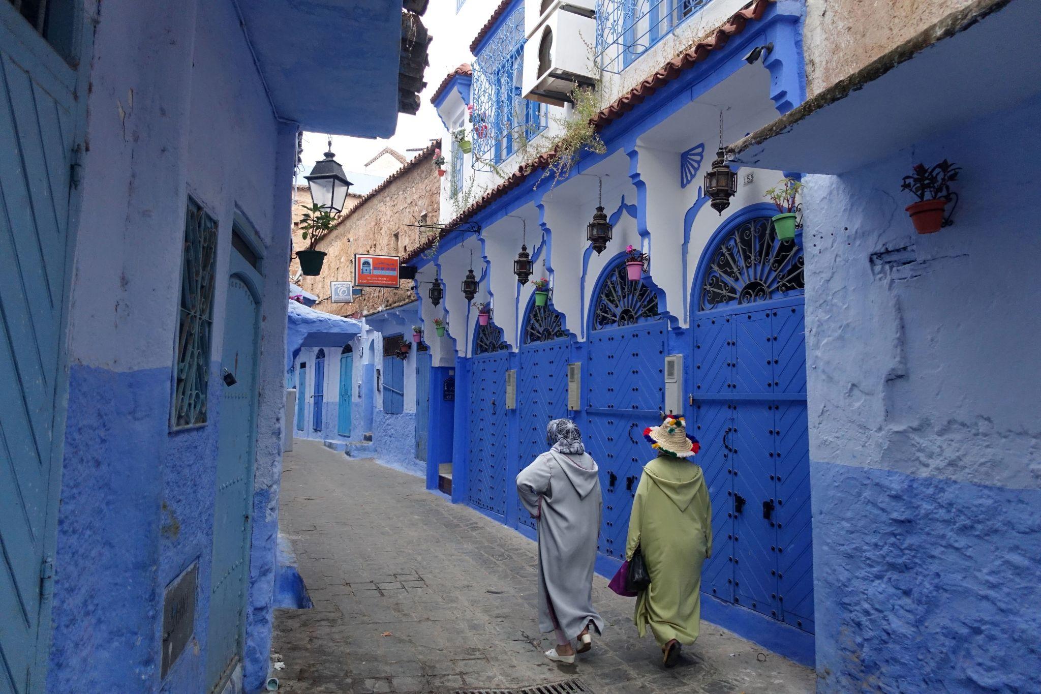 Women wearing traditional clothes and walking in the blue alleys of chefchaouen