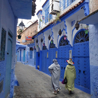 Women wearing traditional clothes and walking in the blue alleys of chefchaouen