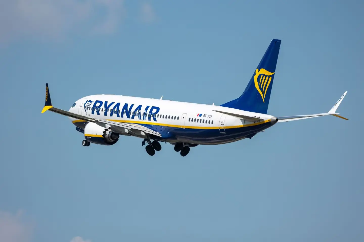 Blue and white Ryanair airplane flying between cities in morocco, against a clear blue sky. The logo is visible on the tail and body. Mid-flight.