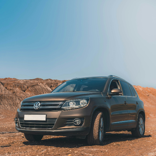 A brown Volkswagen SUV parked on a rocky terrain under a clear blue sky in morocco, exuding a sense of adventure and ruggedness.