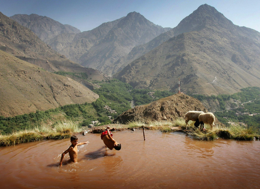 Children happily swimmin in a pond in the atlas mountains of Morocco