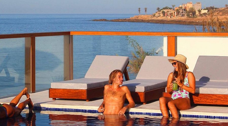 people in a swimming pool havinf fun and sunbathing in taghazout in amouage hotel