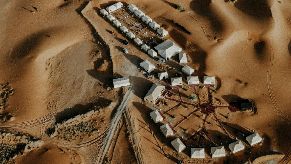 A drone view of a sahara camp in morocco between big dunes