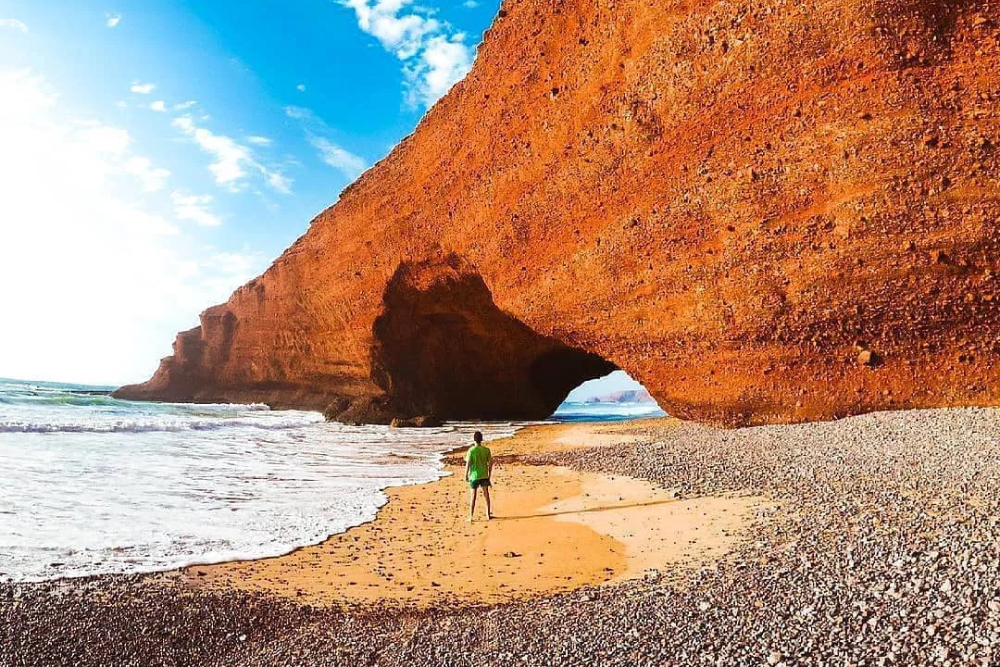 a boy standing near the famous arch in legzira beach near sidi ifni morocco