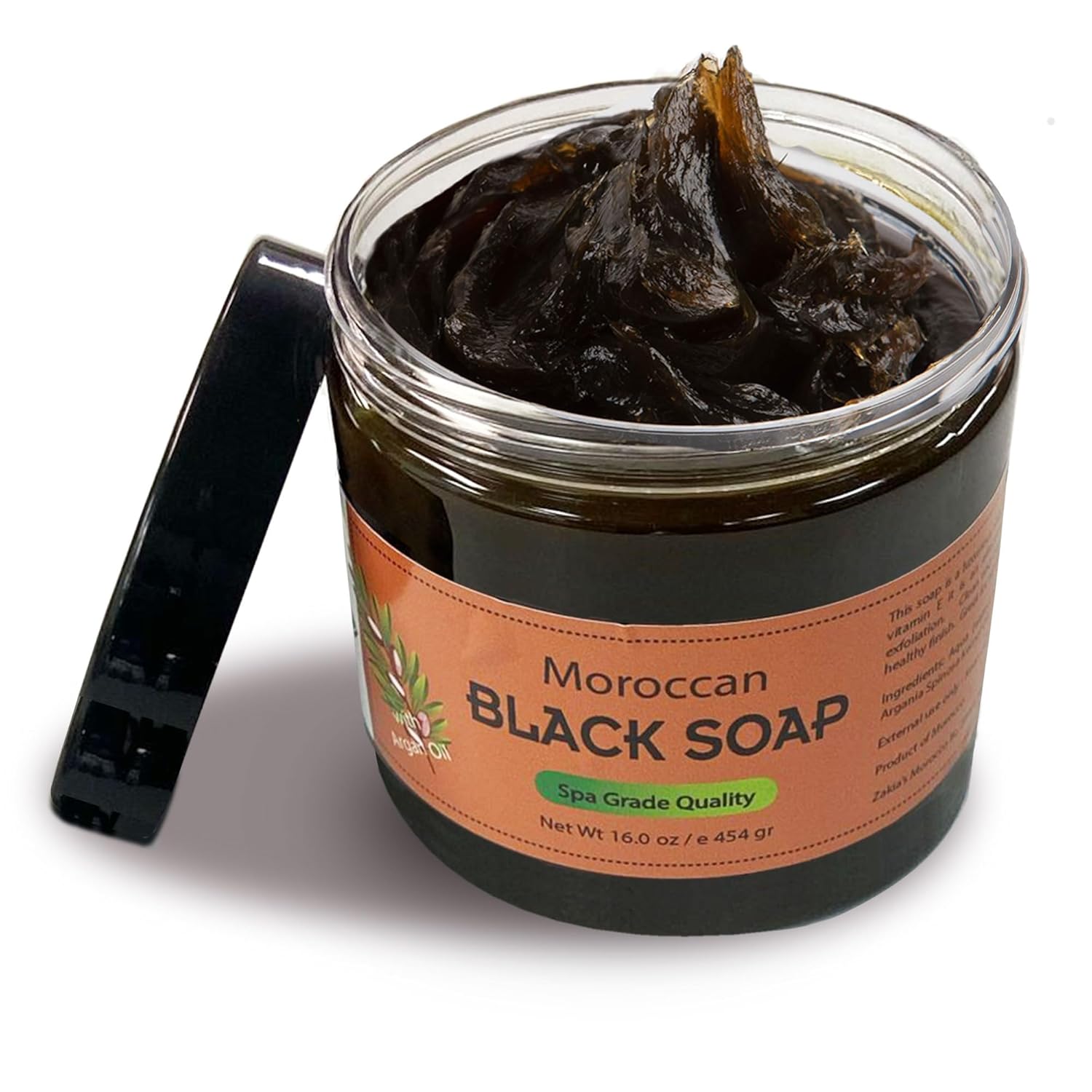 Jar of Moroccan black soap with an open lid, thick dark paste inside. Label reads ‘Spa Grade Quality.’ Prominent text and earthy tones.