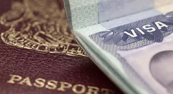 Close-up of a maroon moroccan passport partially covered by a visa page to morocco, displaying the word VISA. Focus on documents, suggesting travel.