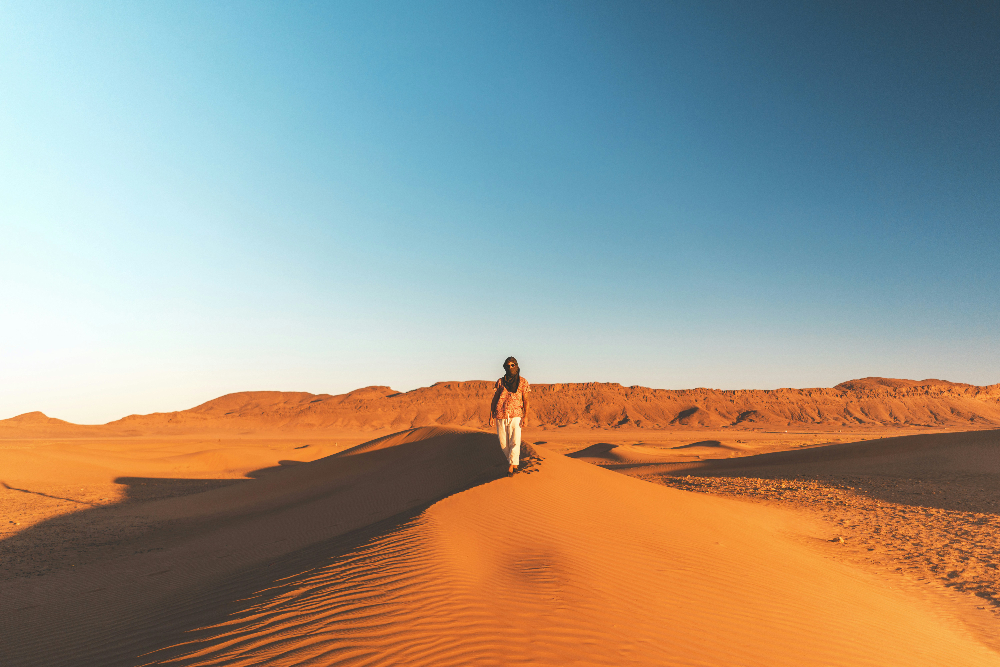 A man standing on a golden dune under a blue sky in the moroccan sahara