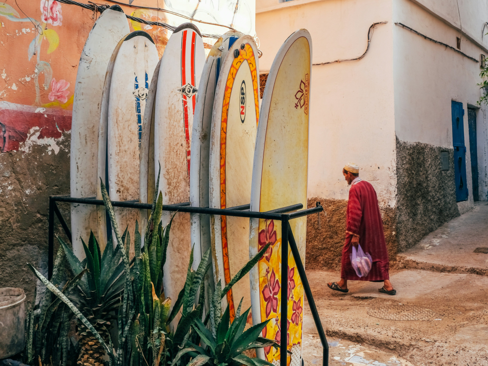 surfboards lined up in taghazout and a local man walking by