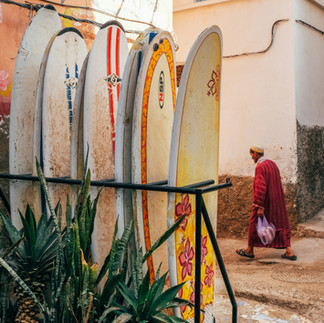 surfboards lined up in taghazout and a local man walking by