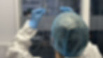 Person in PPE examines objects in Clean Room industrial setting. Hymid logo in background.